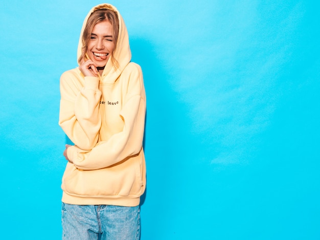 Free photo carefree woman posing near blue wall in studio. positive model having fun,shows tongue and winks