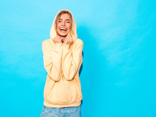 carefree woman posing near blue wall in studio. Positive model having fun