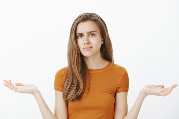 Careless and confused blond girl looking unamused and shrugging, so what gesture