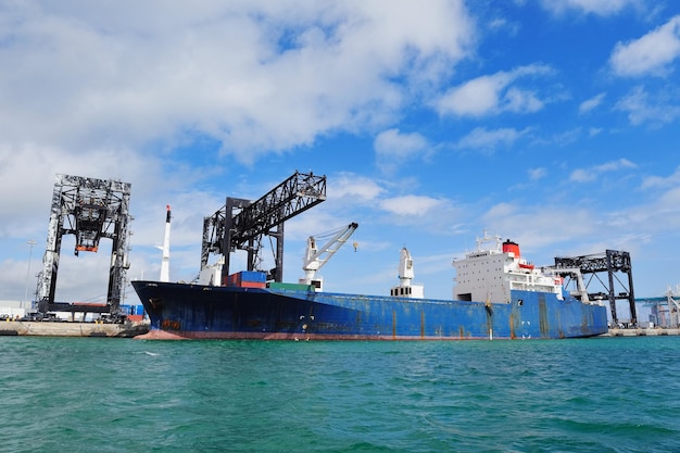 Free photo cargo ship at miami harbor with crane and blue sky over sea.