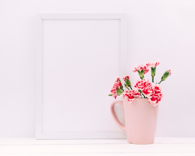 Free Photo carnation flowers in vase with empty photo frame on table