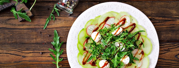 Free photo carpaccio of radish with arugula, mozzarella and balsamic sauce. healthy food. daikon salad. flat lay. top view.