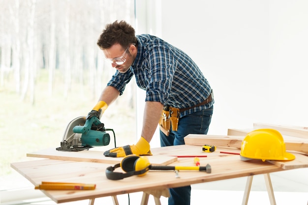 Free photo carpenter cutting plank by circular saw