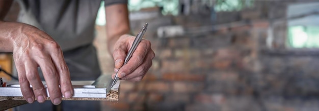 Free Photo carpenter holding ruler and pencil while making marks on the wood