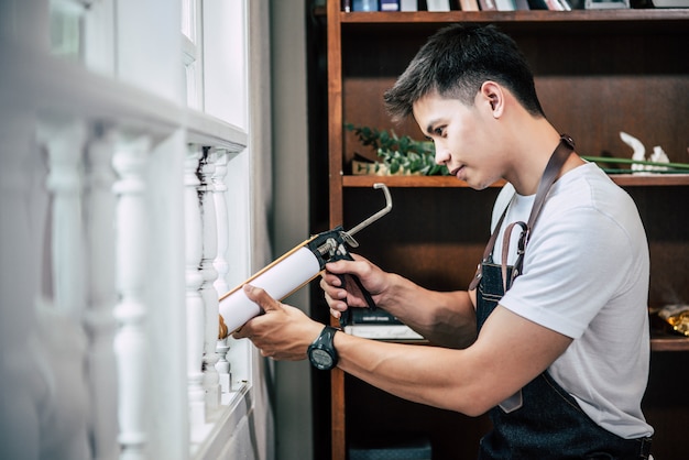 The carpenter holds the glue and attaches to the window.