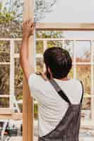 Free photo carpenter man using a tape measure from behind shot