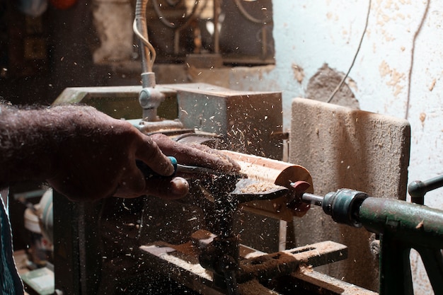 Carpenter peeling woods and shaping them