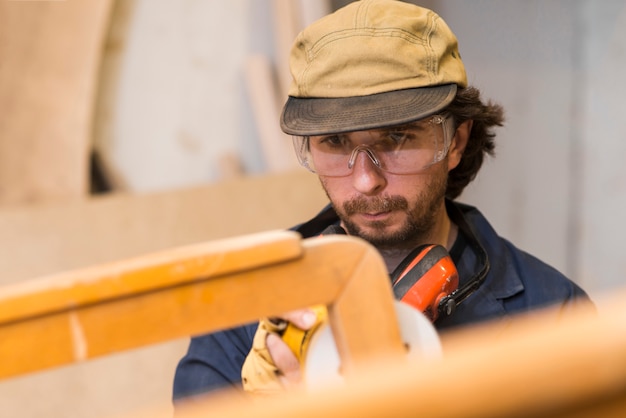 Free photo carpenter polishes wooden furniture with a sander in the workshop