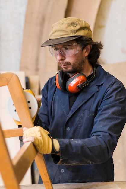 Carpenter polishing wooden furniture with a random orbit sander in the workshop