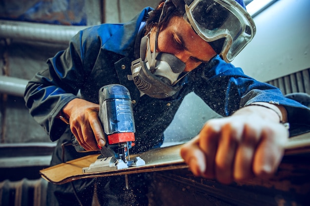 Carpenter using circular saw for cutting wooden boards. Construction details of male worker or handy man with power tools