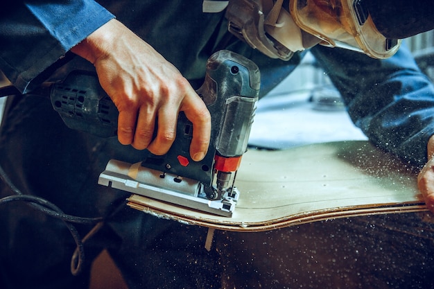 Free photo carpenter using circular saw for cutting wooden boards