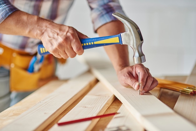 Free photo carpenter with hammer hitting nails