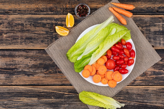 carrot cherry tomato lettuce in a white plate on sackcloth salad ingredients