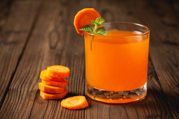 Carrot juice in glass on wooden table.