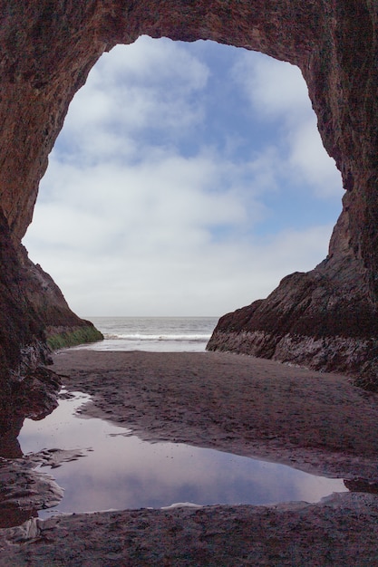 Free Photo a carved cave window by the water