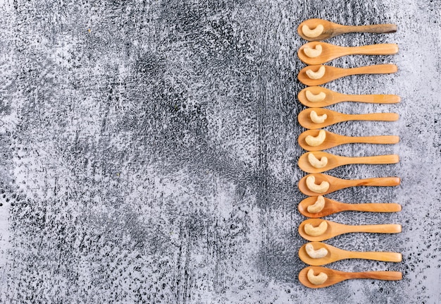 Cashews in a wooden spoons top view on a black stone table