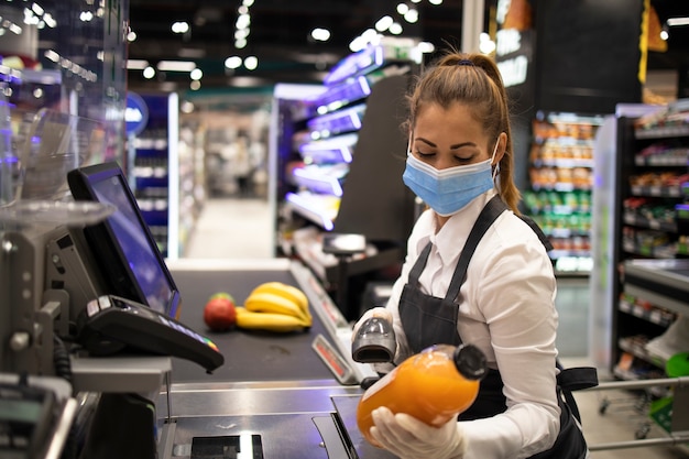 Cashier in supermarket wearing mask and gloves fully protected against corona virus