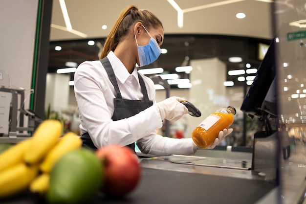 Cashier in supermarket wearing mask and gloves fully protected against corona virus