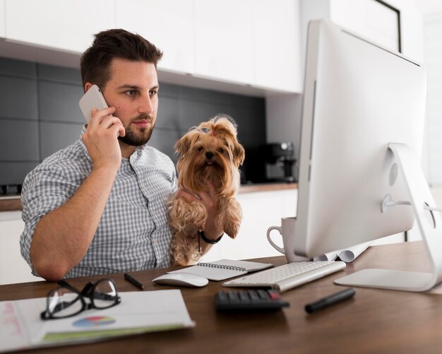 Casual adult male holding pet while working