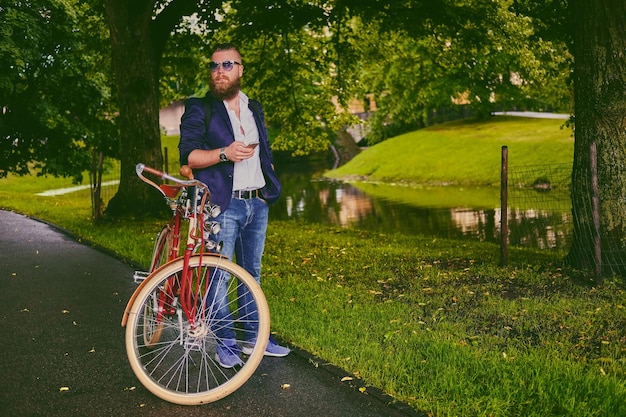 Casual bearded male in a park talks by smart phone.