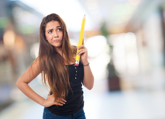 Casual girl holding a big pencil