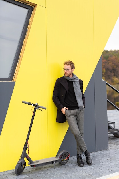 Free photo casual male posing with an electric scooter