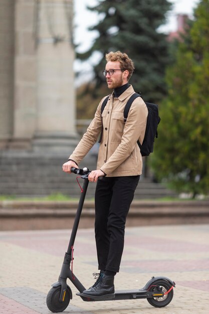 Casual male posing with an electric scooter