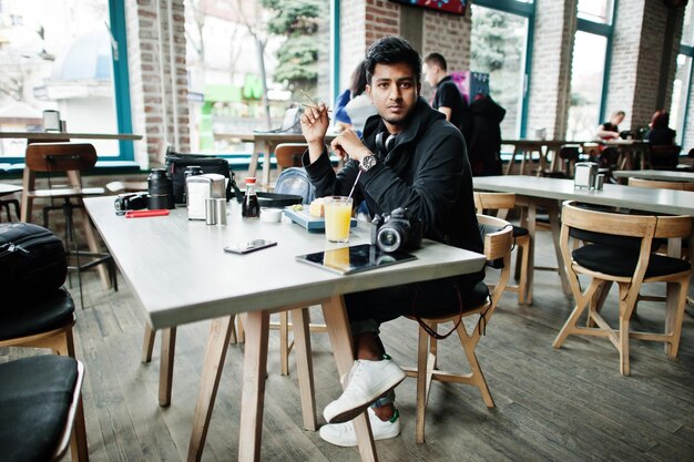 Casual and stylish young asian man with earphones at cafe eating sushi