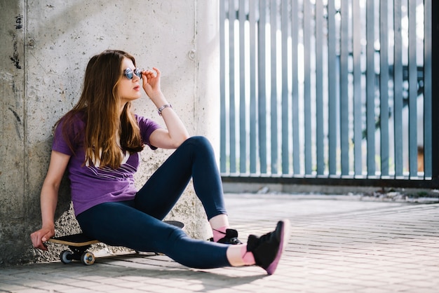 Free photo casual woman sitting on skateboard