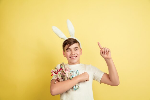 Free photo caucasian boy as an easter bunny on yellow studio background.