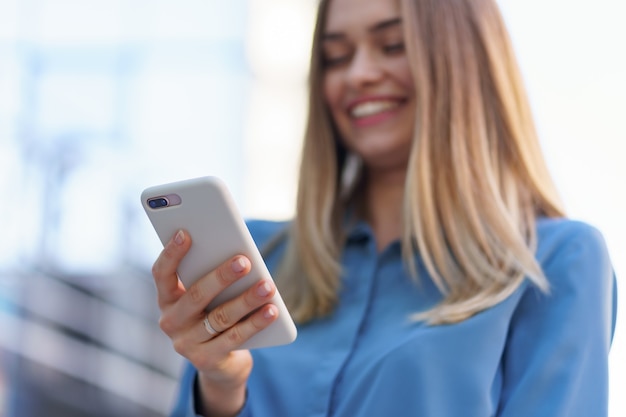 Caucasian business woman speaking by phone holding coffee to go. A successful European woman, talking on the phone, standing on modern office building