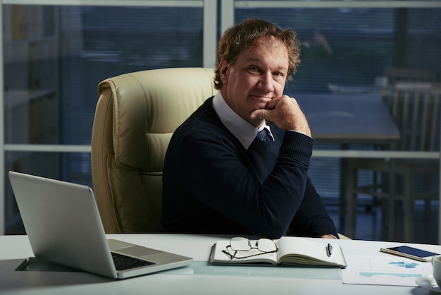 Caucasian entrepreneur seated at his office table with a confident face