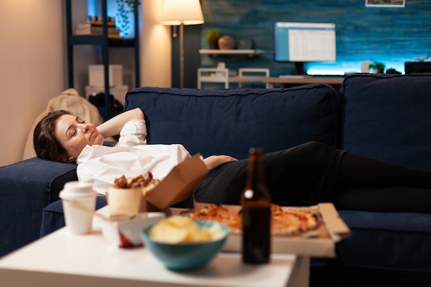 Free Photo caucasian female falling asleep after eating junkfood in living room late at night