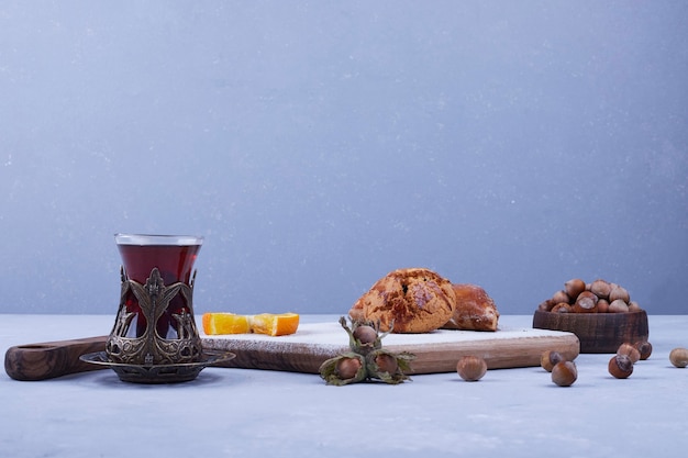 Free photo caucasian kete with sugar powder served with a glass of tea on blue