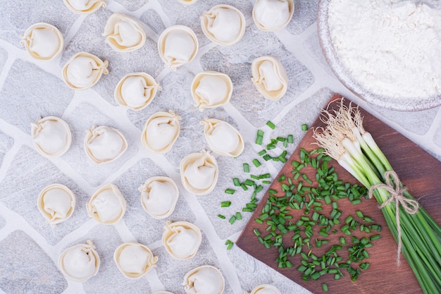 Caucasian khinkali dough on a wooden board with green onions