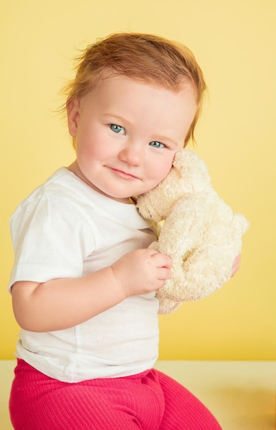 Free photo caucasian little girl, children isolated on yellow studio background. portrait of cute and adorable kid, baby playing and smiling.