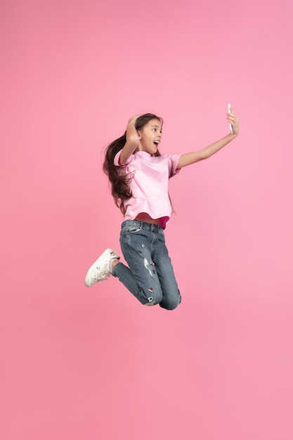 Caucasian little girl portrait isolated on pink studio, emotions concept