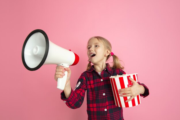 Caucasian little girls portrait on pink studio wall cinema concept