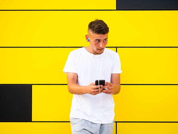 Caucasian male using his phone on yellow wall