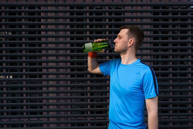 Free photo caucasian man drinking water during exercises