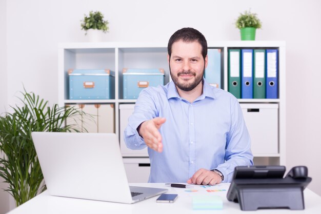 Caucasian man in the office offers cooperation with a handshake