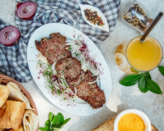 Caucasian meat kebab with onion salad and orange juice.