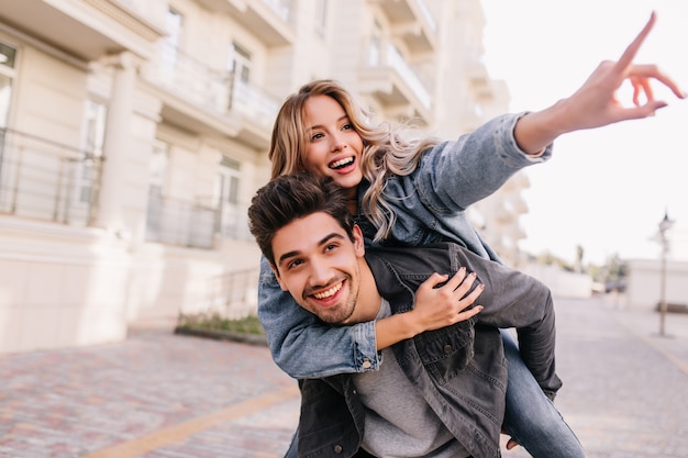 Free photo caucasian pretty girl walking around city with boyfriend. smiling brunette man spending weekend with girlfriend.