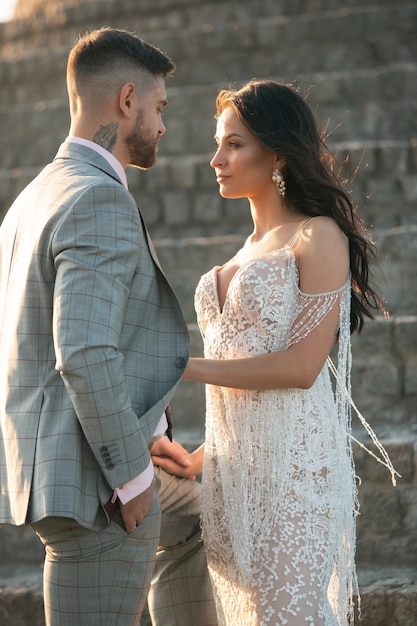 Caucasian romantic young couple celebrating their marriage in city. Tender bride and groom on modern city's street. Family, relationship, love concept