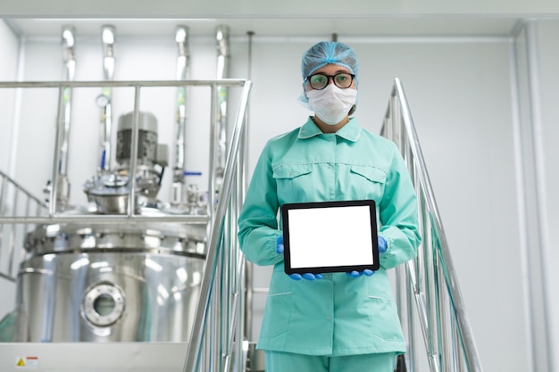 Free photo caucasian scientist in blue lab uniform and glasses stand on chromed stairs and hold empty tablet towards camera