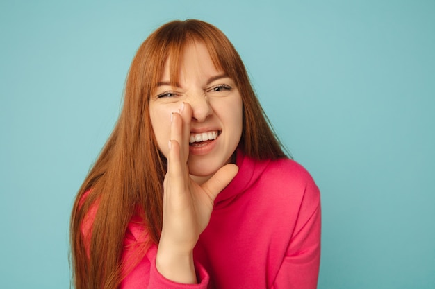 Caucasian shouting woman's portrait isolated on blue studio wall