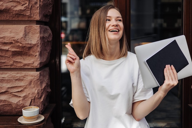 Free Photo caucasian smiling woman holding notebooks and crossing fingers