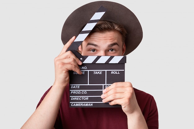 Caucasian successful male producer looks through opened clapperboard