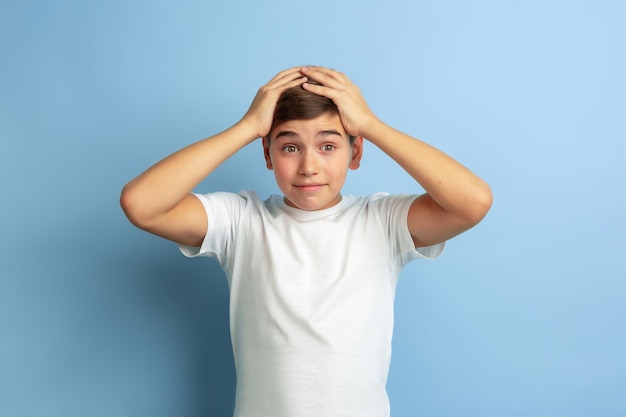 Caucasian teen's portrait isolated on blue studio