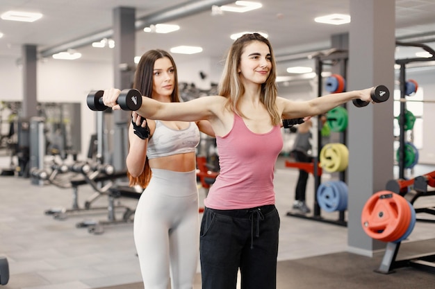 Caucasian woman doing excercisses at gym with personal female trainer